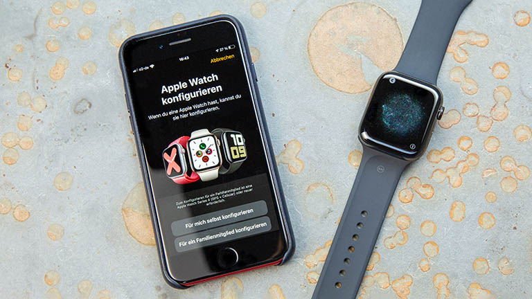 Apple Watch 5 Ein iPhone und eine Apple Watch liegen nebeneinander. Auf dem iPhone ist der Konfigurationsprozess zur Einrichtung der Watch zu erkennen.