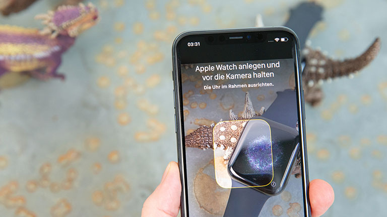 Apple Watch 5 Ein iPhone wird über eine Apple Watch gehalten, um diese einzurichten.