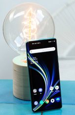 Das OnePlus 8 Pro steht aufrecht angelehnt an eine Glühbirne. Das Display ist aktiviert und zeigt den Home-Bildschirm.