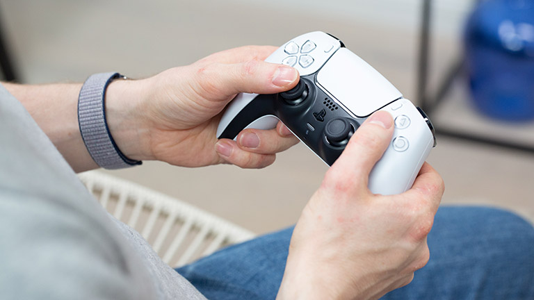 Playstation 5 Eine Person hält den DualSense-Controller der PlayStation 5 leicht schräg ins Bild.