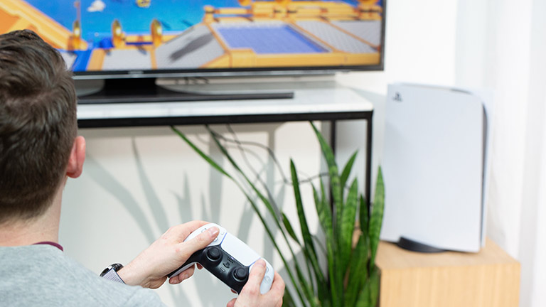 Playstation 5 Eine Person sitzt vor einem Fernseher und spielt auf einer PlayStation 5.