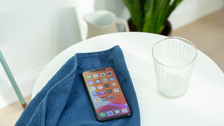 iPhone 11 Ein iPhone 11 liegt auf einem Handtuch. Daneben steht ein Wasserglas.