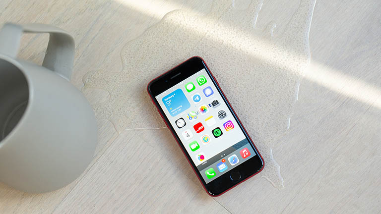 iPhone SE Das iPhone SE inmitten einer verschütteten Flüssigkeit.