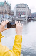 Eine Person hält ihre Smartphone-Kamera auf Gebäude an der kleinen Alster in Hamburg.