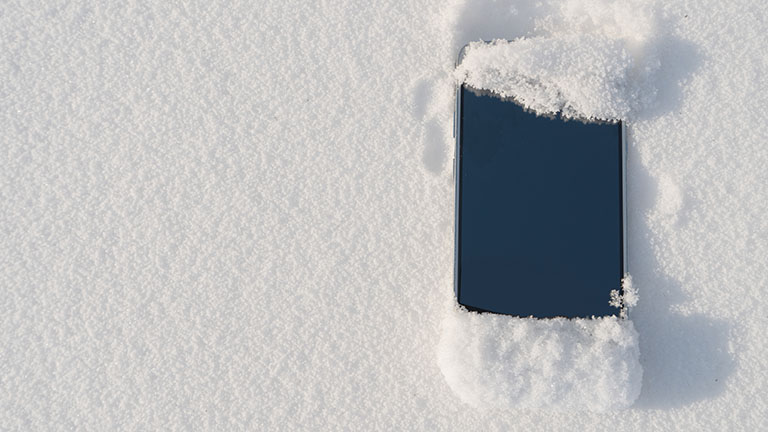 Smartphone im Winter Ein Smartphone liegt im Schnee und ist leicht damit bedeckt.