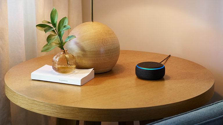 Ein Amazon Echo Dot auf einem kleinen Beistelltisch.