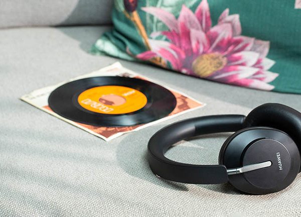 Die Huawei Freebuds Studio auf einem Sofa. Daneben liegt eine Schallplatte.