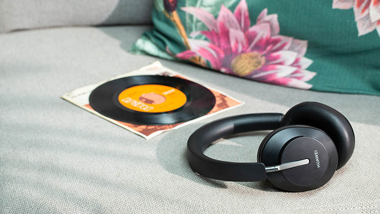 Die Huawei Freebuds Studio auf einem Sofa. Daneben liegt eine Schallplatte.