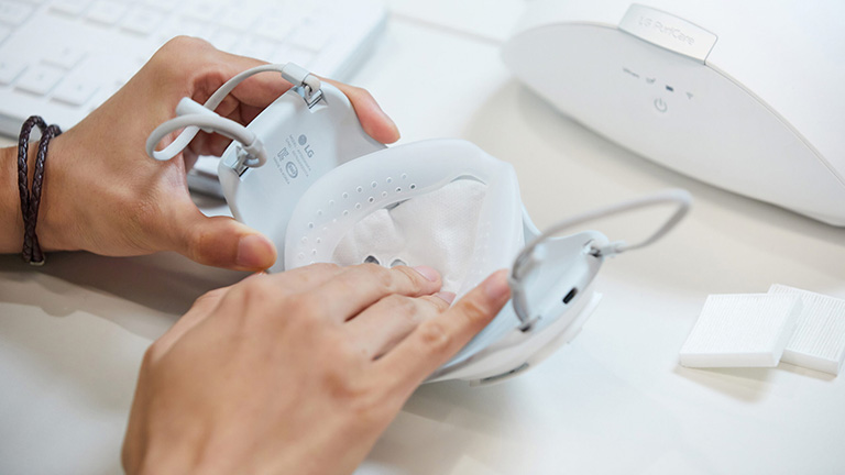 LG PuriCare Wearable Air Purifier Eine Person setzt einen neuen HEPA-Filter in die PuriCare-Maske von LG ein.