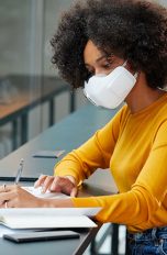 LG PuriCare Wearable Air Purifier Eine Person trägt die PuriCare-Maske von LG, während sie in einem Büro am Laptop arbeitet.