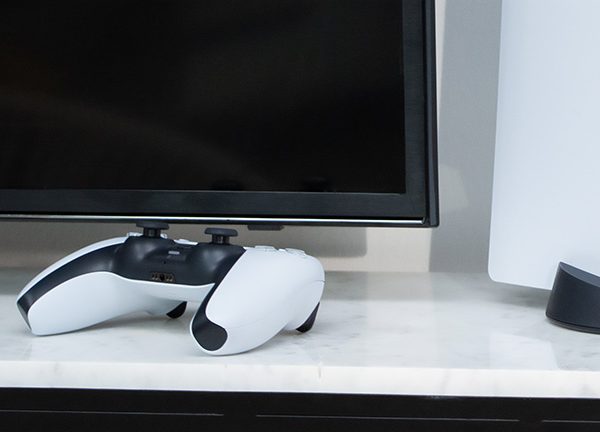 Ein DualSense-Controller neben einer PS5-Konsole.