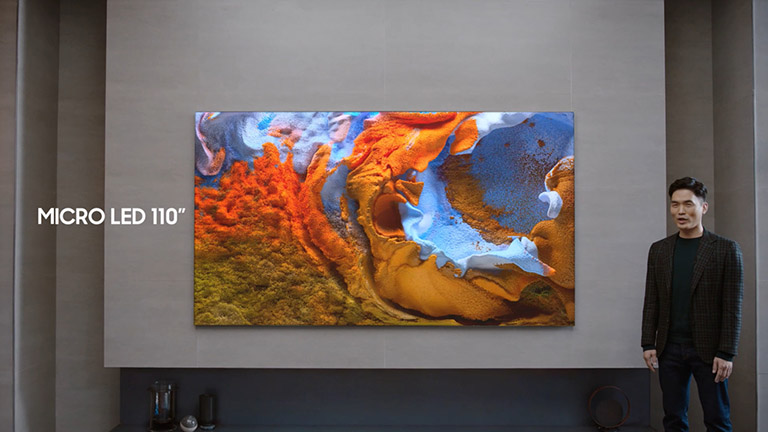 Samsung TV 110 Eine Person steht neben dem 110 Zoll großen Samsung-Fernseher mit Mini-LEDs.
