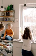 Ein Mann, eine Frau und zwei Kinder befinden sich in der Küche. Die Frau beugt sich über den geöffneten Geschirrspüler.