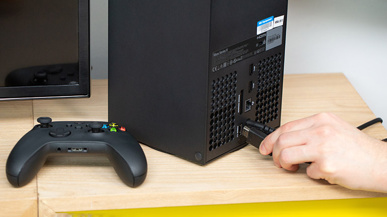 Microsoft Xbox Eine Person steckt ein HDMI-Kabel in den Port hinten an der Xbox Series X.