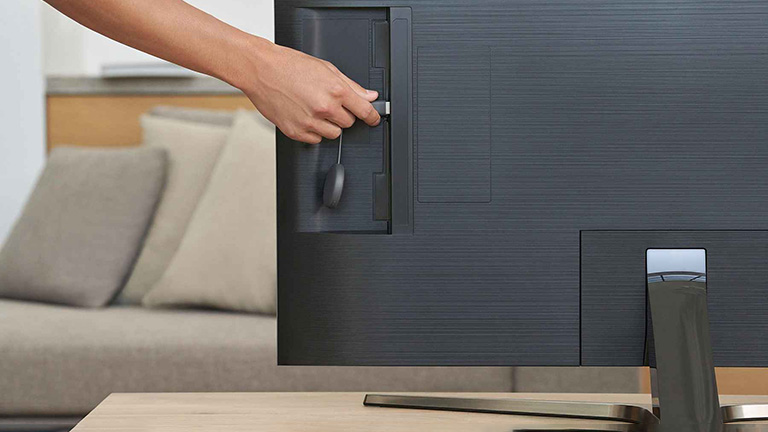 Google Chromecast Eine Person steckt ein Google Chromecast hinten an einem Fernseher an.