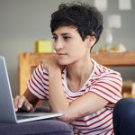 Eine Person sitzt vor einem Laptop.