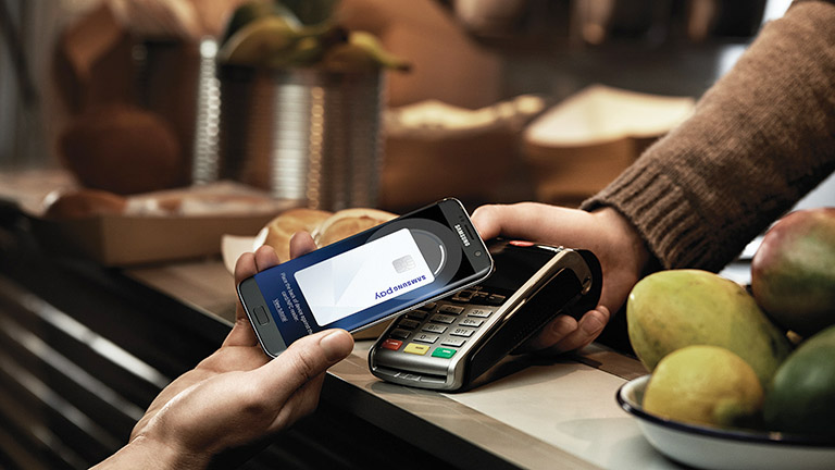 Samsung Pay Eine Person hält ihr Galaxy-Smartphone gegen ein Kartenlesegerät.