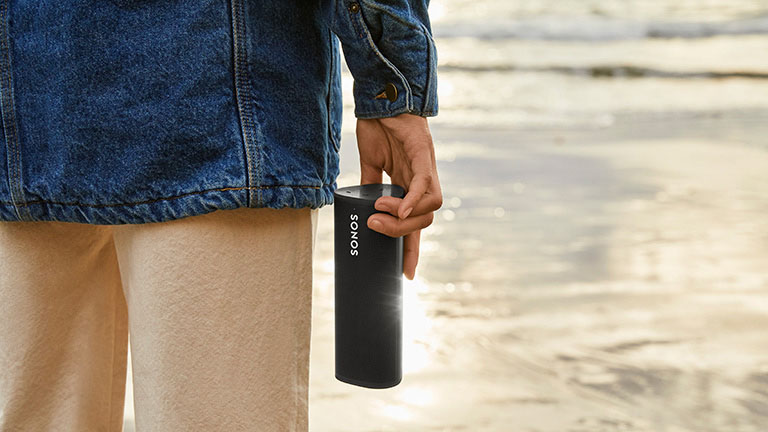 Sonos Roam Eine Person steht am Wasser und hält dabei den Sonos Roam in der Hand.