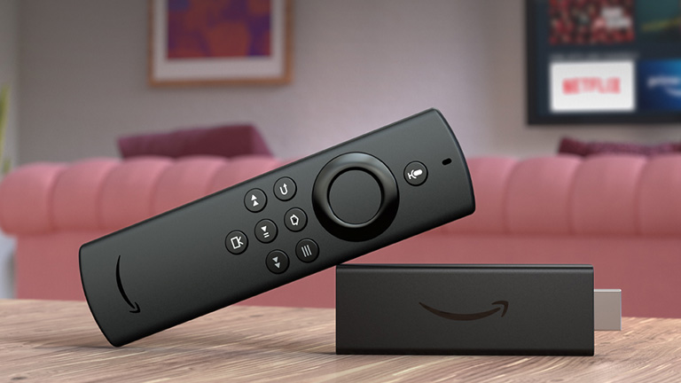 Amazon Fire TV Stick Lite Produktfoto eines Amazon Fire TV Sticks vor einer Couch und einem Fernseher.