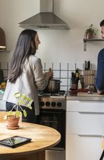 Zwei Personen stehen in einer kleinen Wohnküche und kochen zusammen.