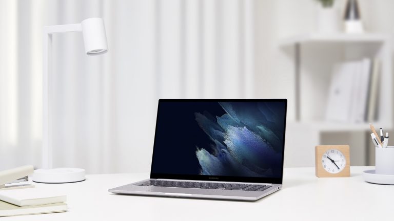 Samsung Galaxy Book Ein Galaxy Book steht aufgeklappt auf einem Tisch neben einer Schreibtischlampe.