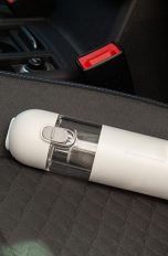 Der Xiaomi Mi Vacuum Cleaner Mini liegt auf einem Autositz mit Stoff-Bezug.