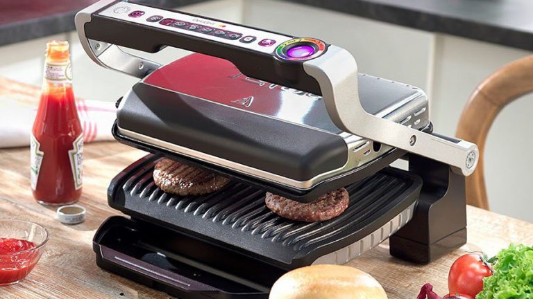 Tefal Optigrill GC705D Ein Tefal Optigrill mit eingelegten Burger-Patties auf einem Küchentisch.