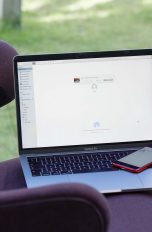 Ein MacBook Pro und ein iPhone SE auf einem Sessel. Die Geräte tauschen gerade Daten per AirDrop aus.