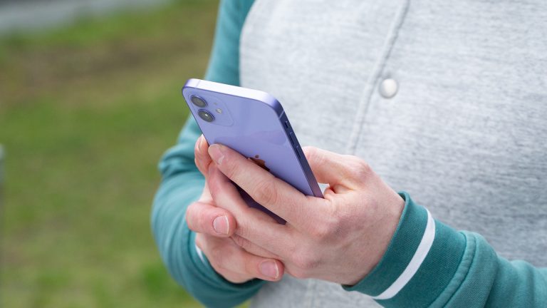 iPhone 12 ine Person hält das iPhone 12 in der neuen Farbe Violett in den Händen.