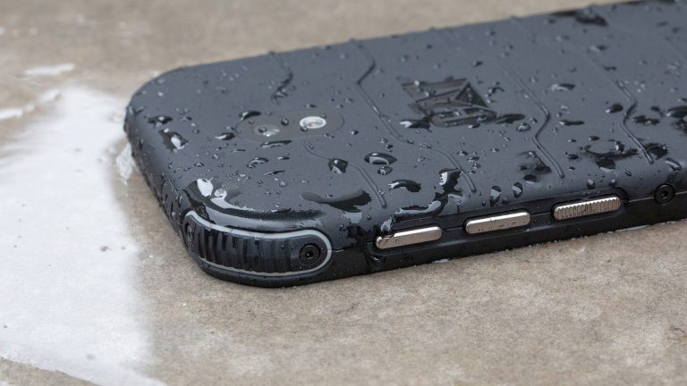 Cat S42 Das Outdoor-Smartphone Cat S42 liegt mit dem Display nach unten auf einem nassen Boden.