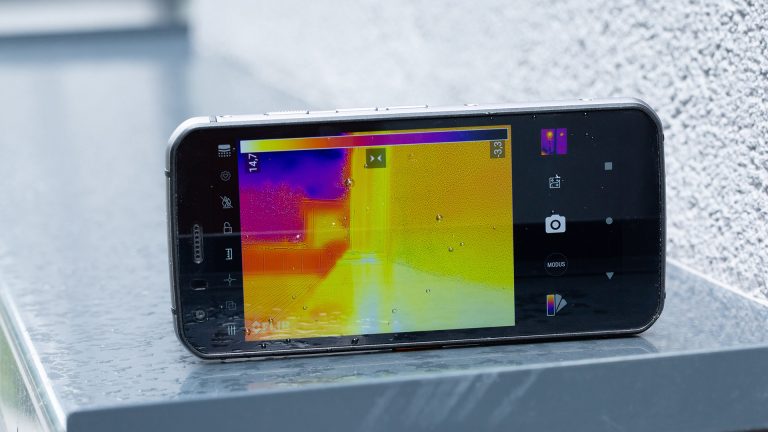Cat S62 Pro Auf dem Outdoor-Smartphone Cat S62 Pro ist die Wärmebildkamera-App geöffnet. Sie ist draußen auf eine Hauswand gerichtet, die im Bild der Kamera orange gefärbt ist.