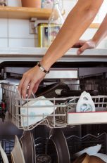 Eine Hand greift in den Geschirrspüler, um ihn auszuräumen