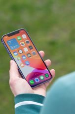 Eine Person hält ein iPhone 12 in der Hand und blickt darauf.