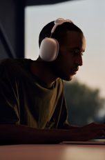 Eine Person mit Apple AirPods Max sitzt vor einem MacBook.