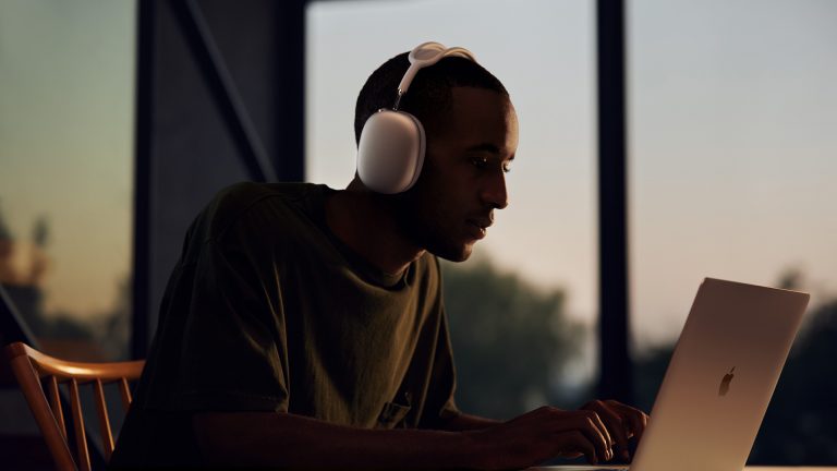 Eine Person mit Apple AirPods Max sitzt vor einem MacBook.