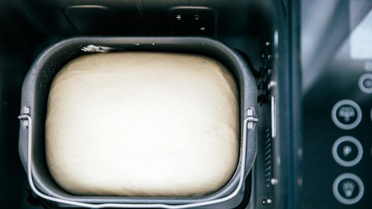 Lebensmittel selbstgemacht Blick von oben in einen Brotbackautomaten, in dem sich ein aufgegangener Brotteig befindet.