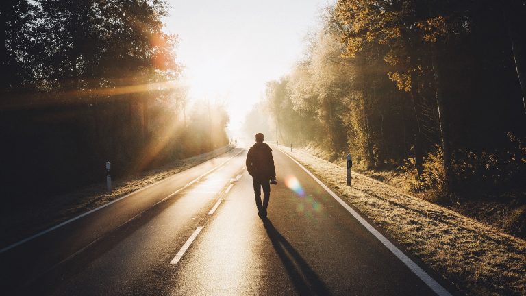 Lens Flare Eine Person läuft auf einer Straße gen Sonne. Diese erzeugt Lens Flare.