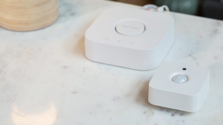Smarthome-Briefkasten Auf einem Tisch liegen die Philips Hue Bridge und der Bewegungsmelder.
