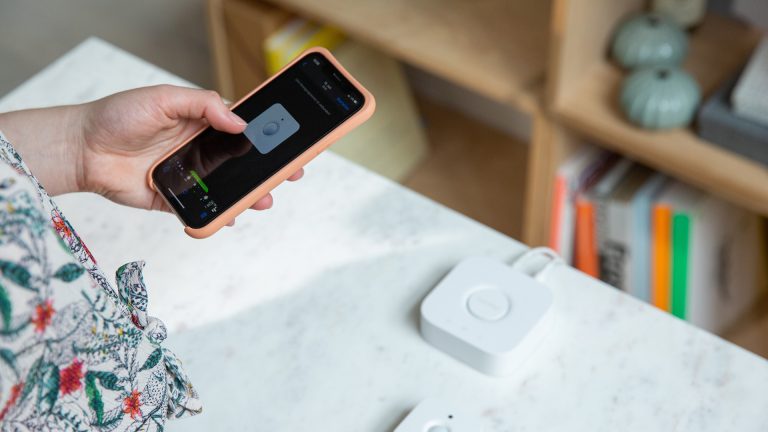 Smarthome-Briefkasten Eine Person richtet die Philips Hue Bridge an ihrem Smartphone ein. Vor ihr liegen die Bridge und der Bewegungsmelder auf einem Tisch.