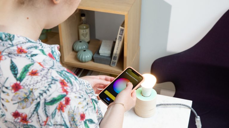 Smarthome-Briefkasten Eine Person stellt die Farbe einer smarten Lampe über die Philips Hue App auf Gelb ein.