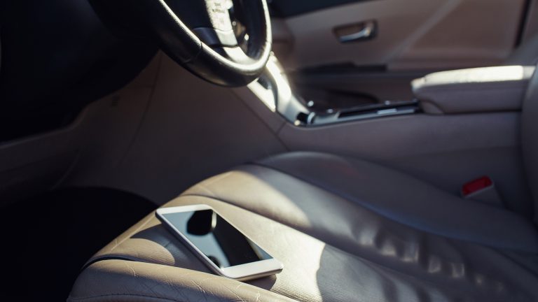 Smartphone im Sommer Ein Smartphone liegt auf dem Vordersitz eines Autos in direkter Sonneneinstrahlung.