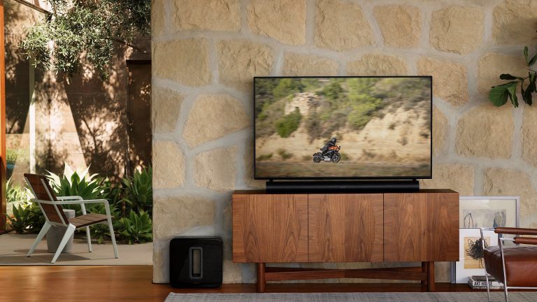 Arc Premium Soundbar Sonos Auf einem edlen Sideboard steht ein Flachbildfernseher, davor eine Soundbar.