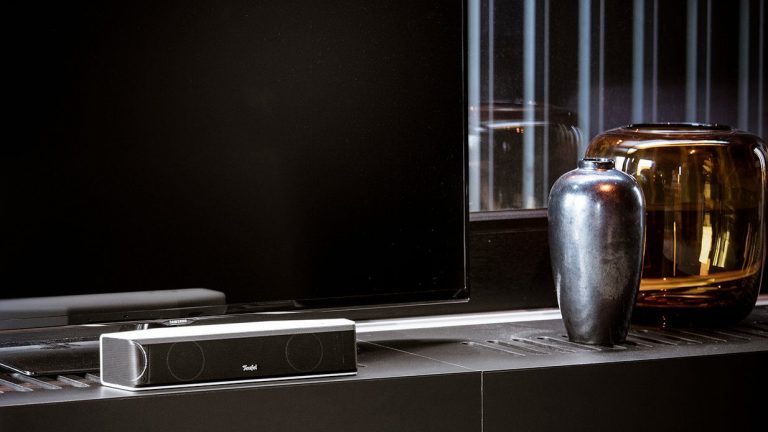 Cinebar One Auf einem Design-Sideboard steht eine Soundbar vor einem Flachbild-TV-Gerät.