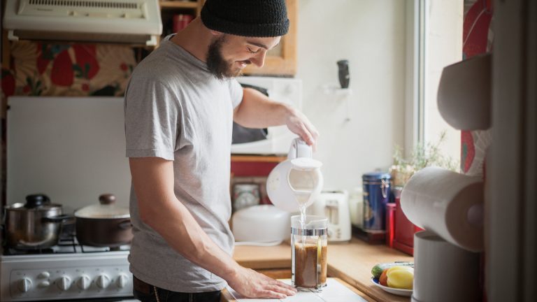 Wasserhärte Eine Person gießt heißes Wasser aus einem Wasserkocher in eine French Press.