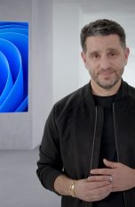 Panos Panay, Chief Product Officer bei Microsoft, steht vor der Kamera. Im Hintergrund ist das Logo von Windows 11 zu sehen.