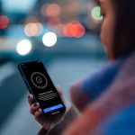 Eine Frau blickt auf ihr iPhone. Darauf ist die Einrichtung für Face ID zu sehen.