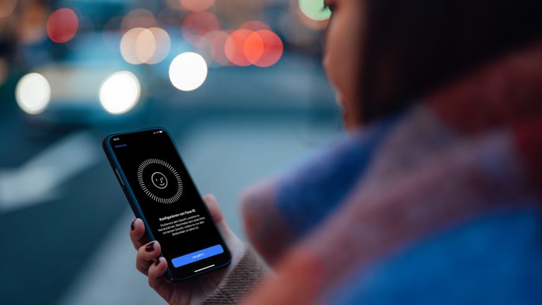 Eine Frau blickt auf ihr iPhone. Darauf ist die Einrichtung für Face ID zu sehen.