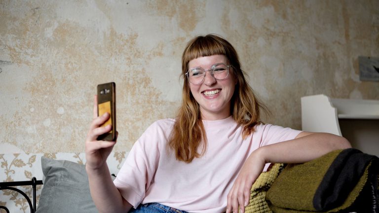 FaceTime Eine Person lehnt an einem Sofa und telefoniert per Video.