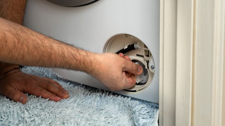 Flusensieb klemmt Eine Person dreht am Deckel eines Flusensiebs bei einer Waschmaschine.