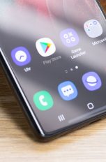 Ein Smartphone lehnt an einem Gegenstand. Im Detail ist auf dem Bildschirm der Google Play Store zu sehen.